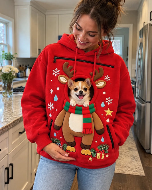 Woman in a kitchen wearing the red Paw Hoodie with a chihuahua's head through the reindeer opening and its front paws resting on the scarf